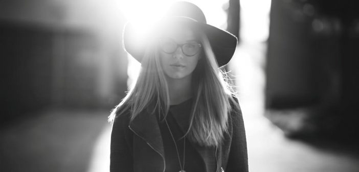 foto en blanco y negro de una mujer con sombrero en una calle soleada