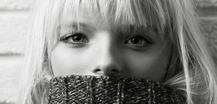 puede la ansiedad causar síntomas físicos: mujer con suéter sobre la boca