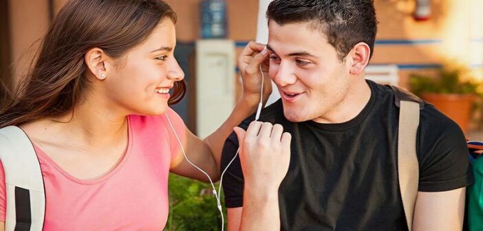 sonriente joven y mujer compartiendo auriculares que ilustran la química entre las personas