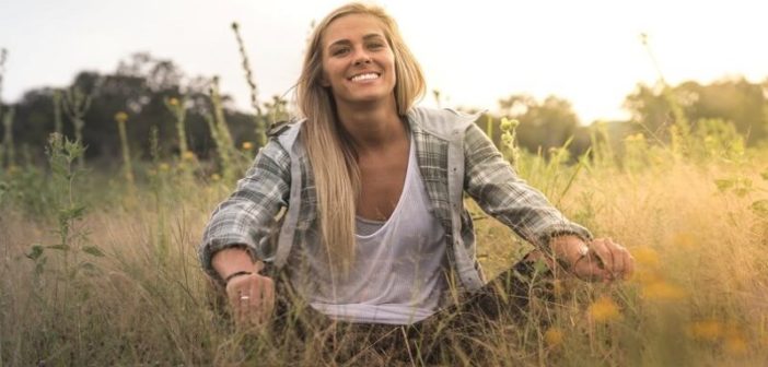 mujer emocionalmente independiente, sonriendo sentada en un campo de hierba