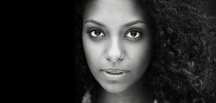 Mujer afroamericana en blanco y negro mirando a la cámara - autocuidado emocional