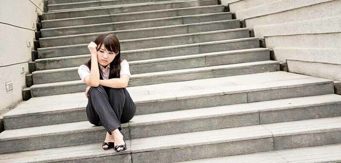 joven empresaria ansiosa sentada en unos escalones que ilustran el miedo al éxito
