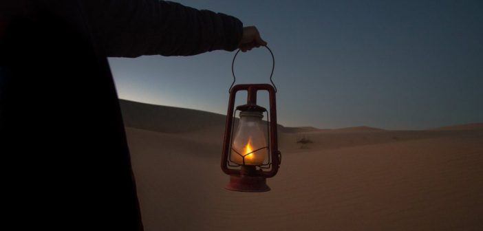 hombre sosteniendo linterna en el desierto