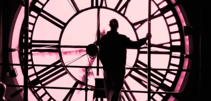 hombre parado frente a una enorme esfera del reloj, ilustrando la idea de retroceder en el tiempo y cambiar las cosas