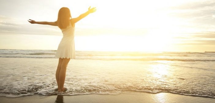 mujer feliz en la playa con los brazos en alto