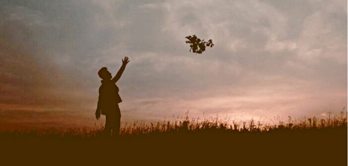 silueta de persona lanzando flores al cielo, dejando así de lado el pasado