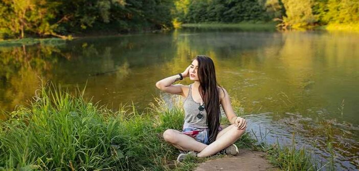 joven sentada junto al lago, ilustrando una vida plena