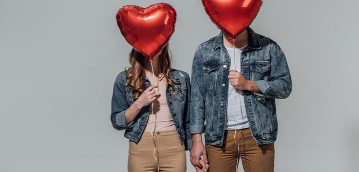 novio y novia con caras ocultas por globos en forma de corazón