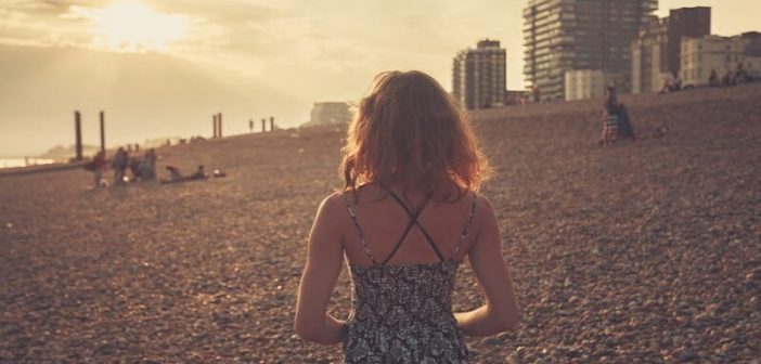 mujer caminando sola en la playa al atardecer