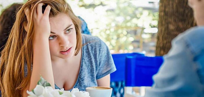 mujer luciendo frustrada con su novio en un café, ilustrando una relación de amor y odio