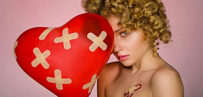 mujer sosteniendo globo cardíaco con yesos por todas partes ilustrando el dolor y el dolor del amor
