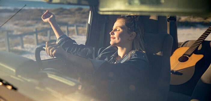 mujer sentada en el auto disfrutando del sol, haciendo que cada día cuente