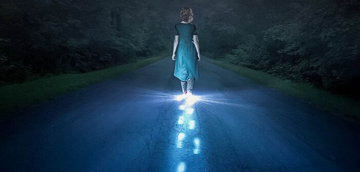 persona caminando en la oscuridad con pasos brillantes de luz - ilustrando la recuperación del abuso narcisista