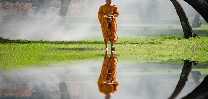 Un monje budista caminando con reflexión en el agua - concepto de Nirvana