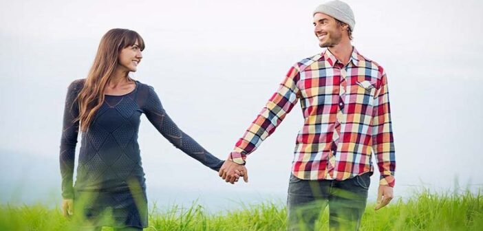 pareja tomados de la mano caminando por el campo cubierto de hierba ilustrando paciencia en una relación
