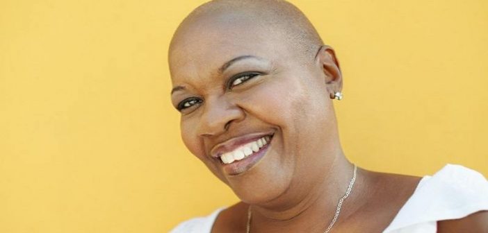 mujer negra sonriente sobre fondo amarillo - concepto de actitud mental positiva