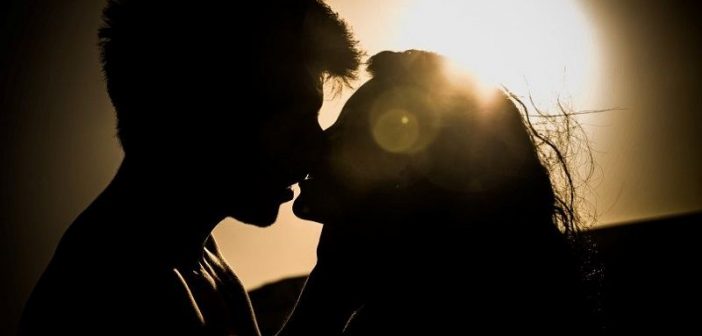 silueta de una joven pareja besándose contra el sol - ilustrando mitos de relación