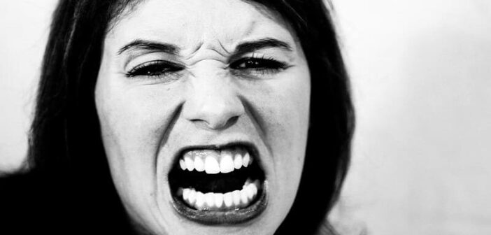 mujer con aspecto enfadado reaccionando a algo estresante cuando debería responder en su lugar