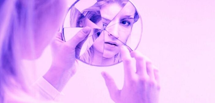 concepto de autodesprecio ilustrado con una mujer que se mira en un espejo agrietado