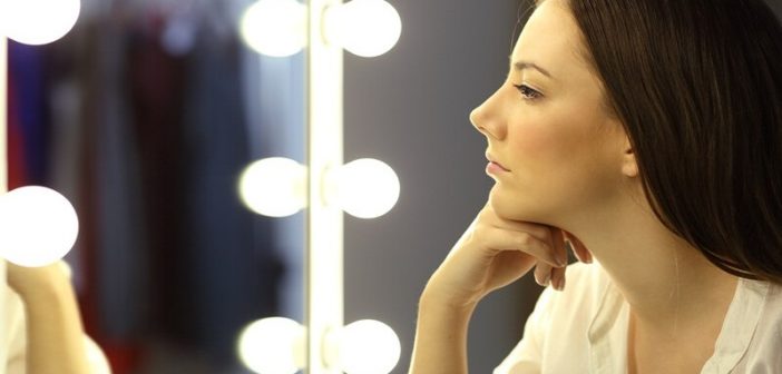 mujer mirando su reflejo en un espejo para ilustrar las preguntas de autorreflexión