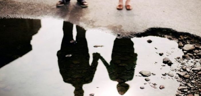 reflexión en un charco de pareja tomados de la mano ilustrando una situación
