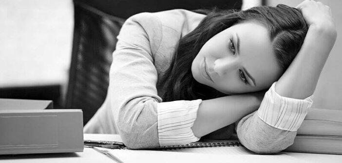 mujer exhausta mirando sin esperanza en su escritorio, ilustrando estar cansada de la vida