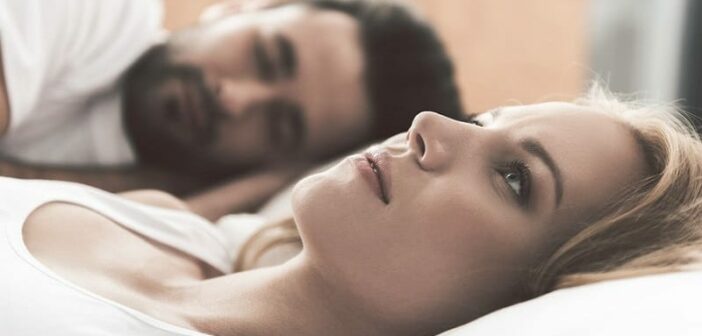mujer acostada en la cama junto a una pareja infeliz en la relación, pero todavía lo ama