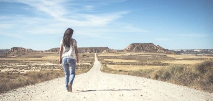 mujer caminando por el camino del desierto hacia el horizonte ilustrando estableciendo una meta