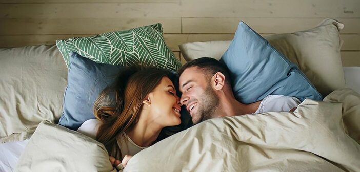 hombre y mujer felices en la cama, ilustrando lo que un hombre quiere en una mujer