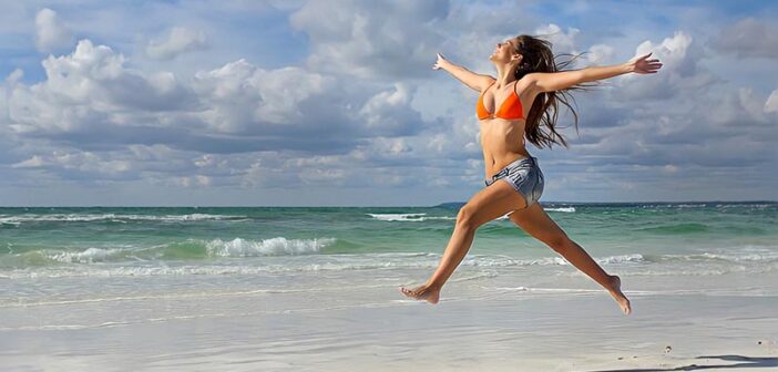 mujer saltando y celebrando en una playa ilustrando ganar en la vida