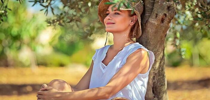 peaceful looking woman sitting under a tree - illustrating not letting things bother you