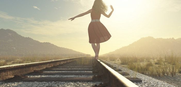 mujer caminando por la vía del ferrocarril al sol