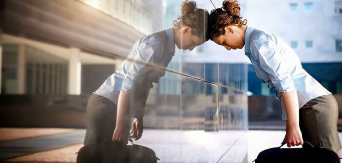 empresaria inclinada cabeza contra edificio de vidrio que ilustra el agotamiento y sus síntomas