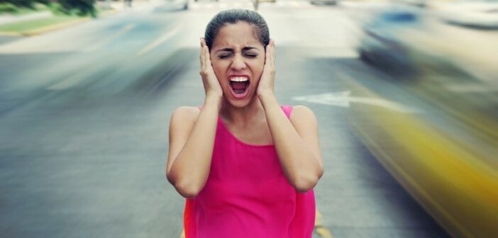 mujer gritando sosteniendo sus oídos mientras el tráfico pasa, ilustrando un mundo que se está volviendo loco
